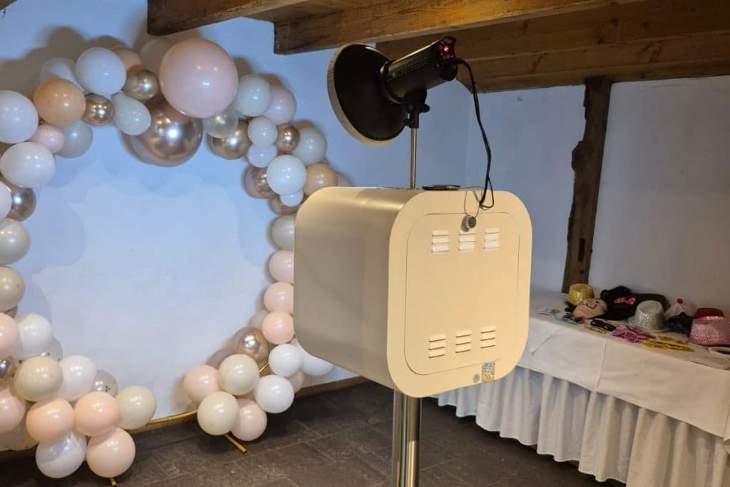 Weiße Fotobox vor einem Ballonbogen in einer Hochzeitslocation